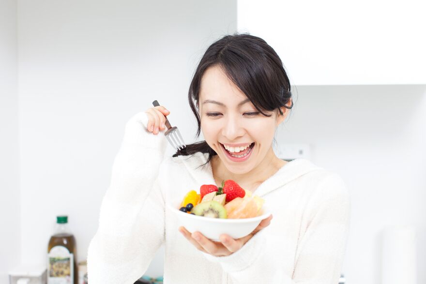女性がお皿山盛りの果物を食べている様子